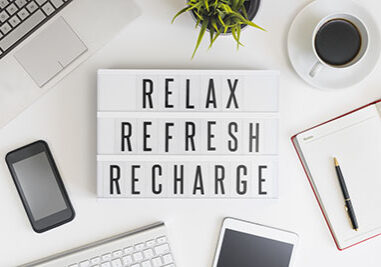 Relax, refresh and recharge words on office table with computer, coffee, notepad, smartphone and digital tablet